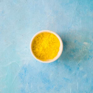 Bol de poudre de maca jaune pure sur fond bleu, complément alimentaire naturel, racine andine traditionnellement utilisée pour accompagner la vitalité au quotidien