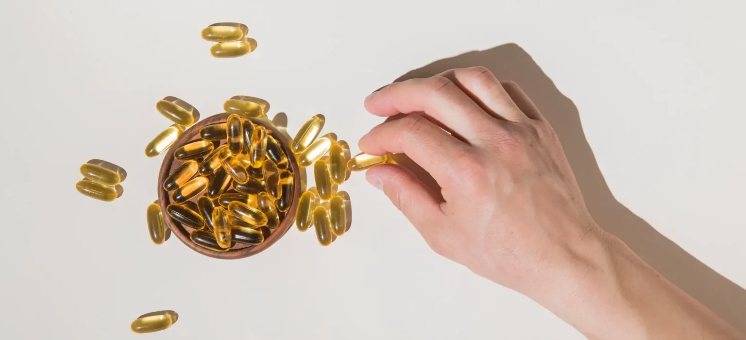 Main prenant des capsules d omega 3 illustrant le dosage journalier recommande en EPA DHA et ALA